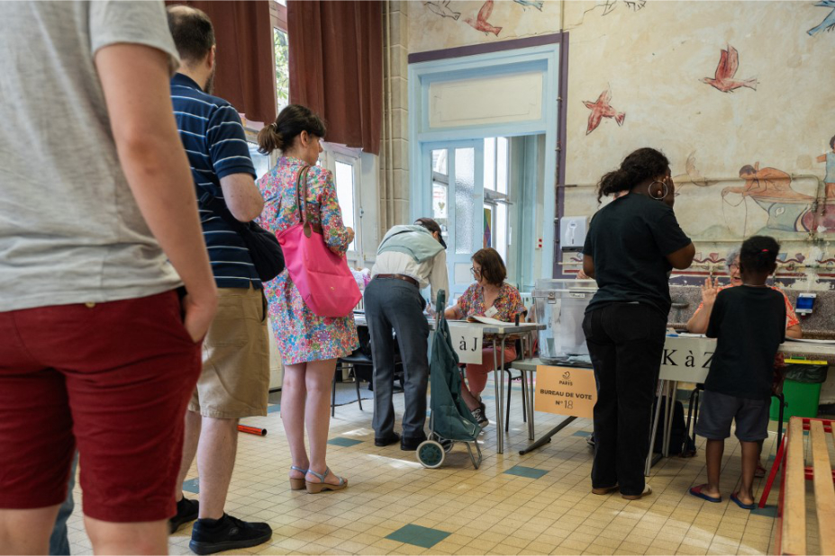Lors du 1er tour des élections législatives, des Français font la queue dans un bureau de vote à Paris.