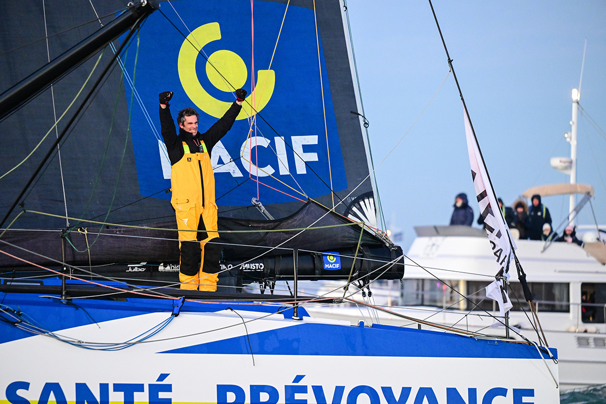 Charlie Dalin sur son bateau, levant les bras en signe de victoire.