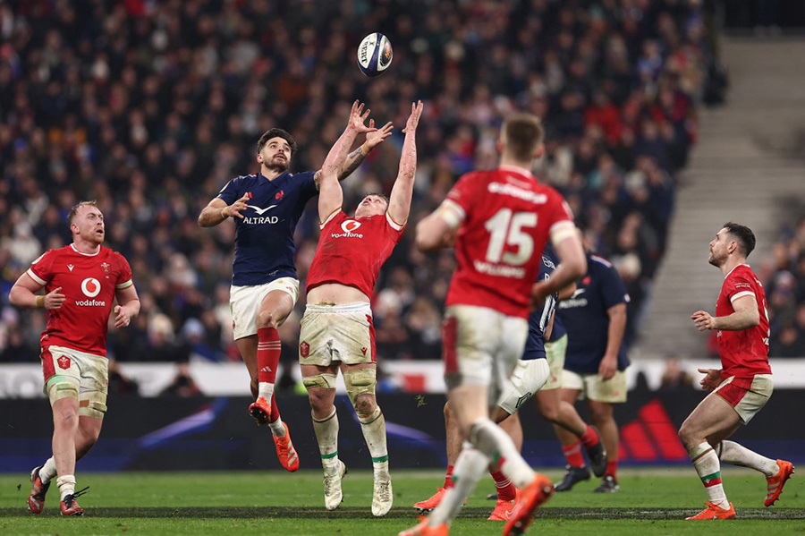 Pendant le match opposant la France et le Pays de Galles, le Français Romain Ntamack tente d'attraper le ballon avant son adversaire.