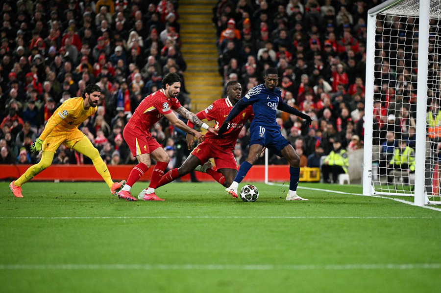 Le joueur en bleu Ousmane Dembélé marque un but en enjambant ses adversaires en rouge. 